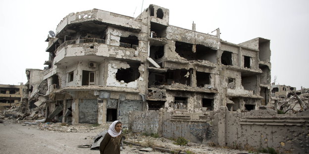 eine Frau vor einer Ruine in Homs