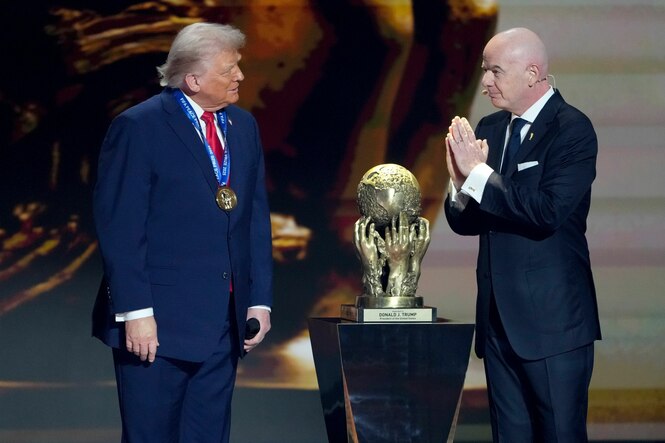 Infantino steht mit gefalteten Händen vor Trump, zwischen ihnen der Fifa-Friedenspreis