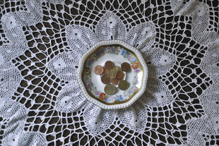 Eine gehäkelte Tischdecke mit einer Schale Münzen