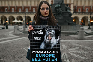 Frau hält ein Schild mit einem Nerz im Käfig