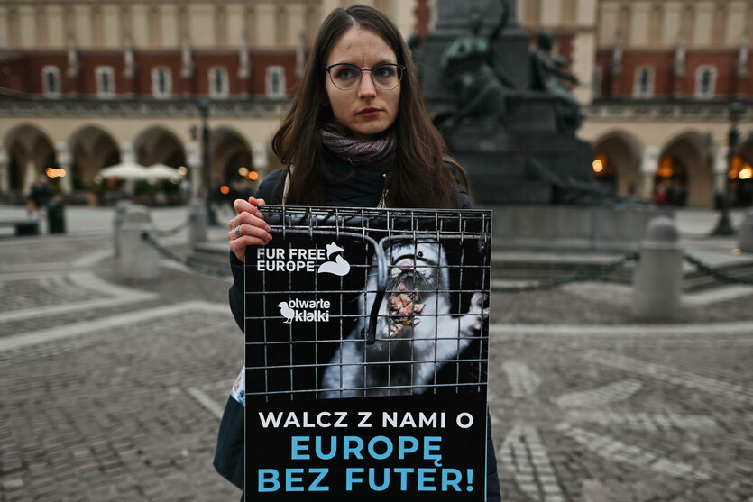 Frau hält ein Schild mit einem Nerz im Käfig