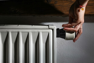 Eine Hand dreht an einer Heizung