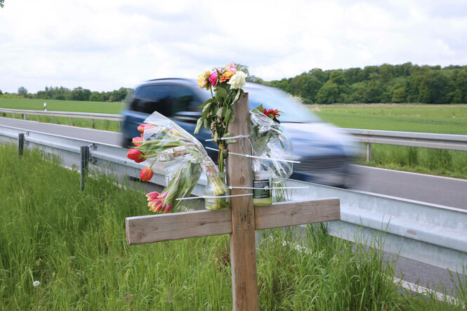 Ein Kreuz mit Blumen an einer Landstraße