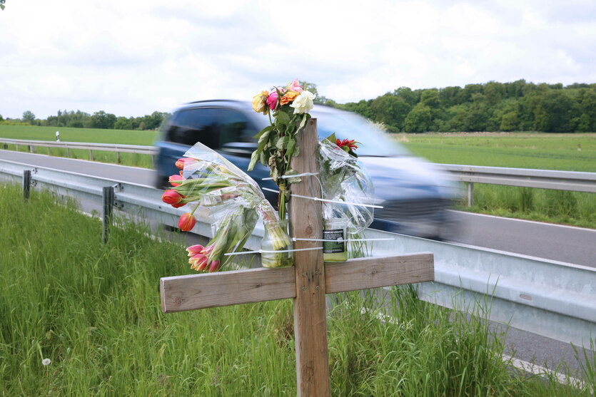 Ein Kreuz mit Blumen an einer Landstraße