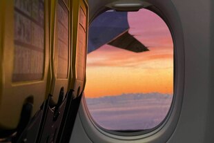 Blick aus dem Flugzeugfenster auf die Wolken während die Sonne untergeht