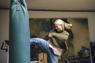 Frau übt an einem Boxsack Kickboxen