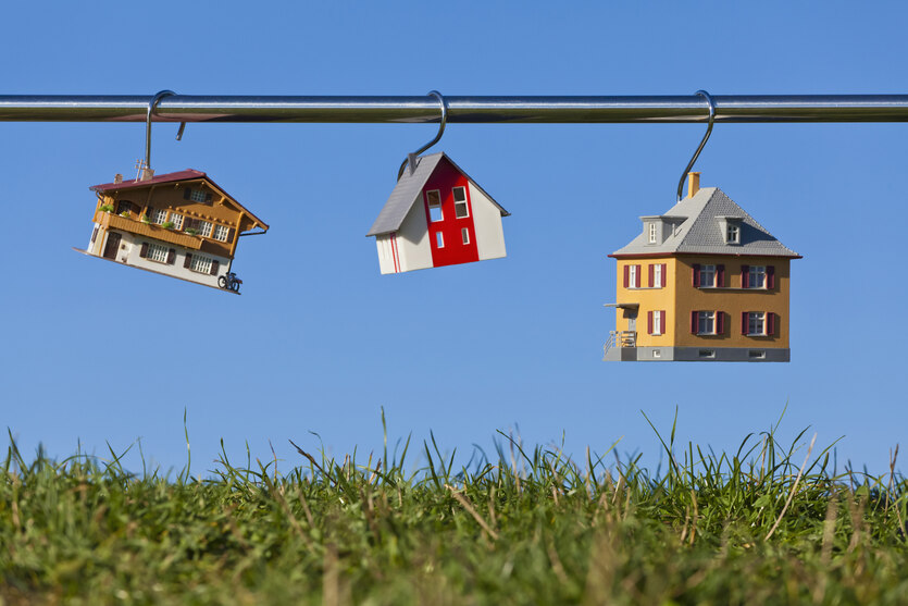 Miniaturhäuser hängen an einer Stange über einer Wiese