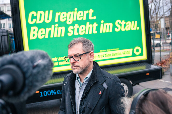 Ein Mann steht vor einem Plakat: 