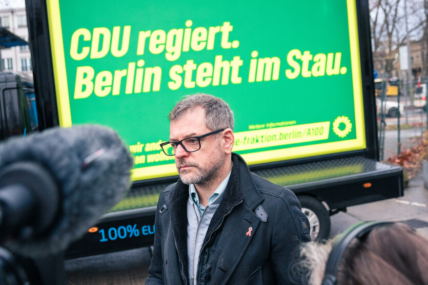 Ein Mann steht vor einem Plakat: "CDU regiert. Berlin steht im Stau."