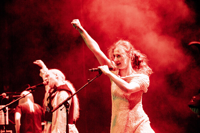 Pussy Riot auf der Bühne mit rotem Nebel, zwei Frauen am Mikrofon singen mit erhobener Faust