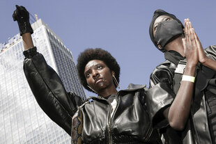 Zwei Personen posieren mit ernstem Blick, eine reckt die Faust in die Höhe