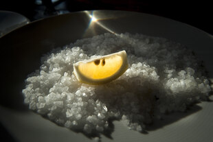 Ein Zitronenstück liegt auf grobem Salz