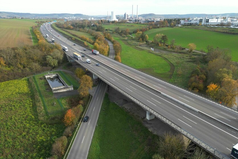 Kaum befahrene sechspurige Autobahn zieht sich durch die Landschaft, im Hintergrund Industrie