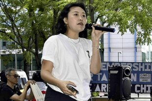 Carmen Lau steht an einem sonnigen Tag auf einem Platz mit dem Mikrofon in der Hand