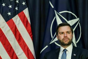 Eine Mann (J. D. Vance) vor einer US-Flagge und einer Nato-Flagge