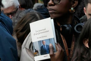 Eine Frau hält ein Buch des ehemaligen französischen Präsidenten Nicolas Sarkozy mit dem Titel „Tagebuch eines Gefangenen“
