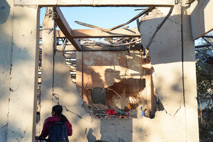 Eine Frau vor einem zerstörten Krankenhaus