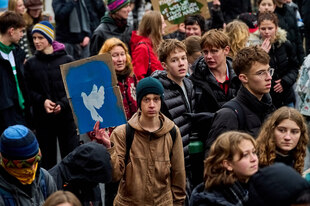 Protestierende in Winterkleidung, ein Mensch hält ein Schild mit einer Friedenstaube