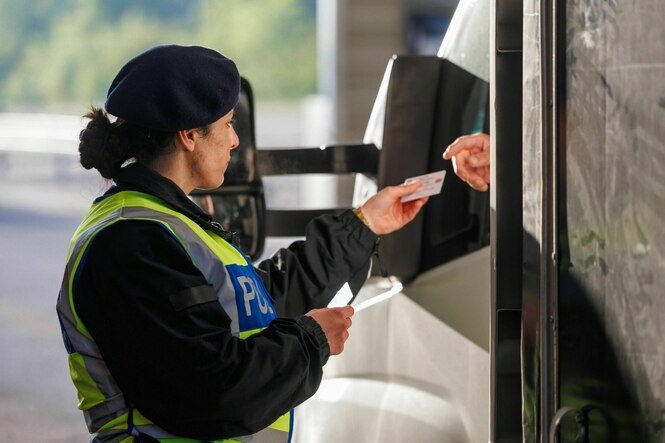 Eine Polizeibeamtin kontrolliert den Fahrer eines Autos