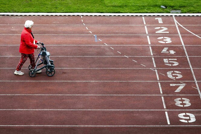 Eine Seniorin mit Rollator auf einer Tartanbahn kurz vor dem Ziel