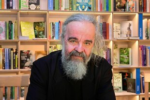 Ein Mann schaut in die Kamera, hinter ihm steht ein Buchregal