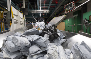 Ein Berg an Postsendungen liegt auf einem Förderband.