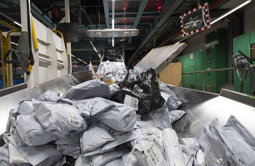 Ein Berg an Postsendungen liegt auf einem Förderband.