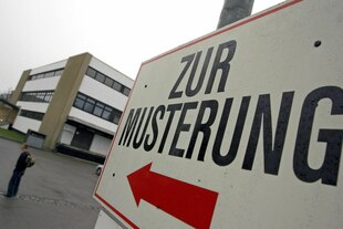 Ein Schild, auf dem "Zur Musterung" steht und ein roter Richtungspfeil zu sehen ist.