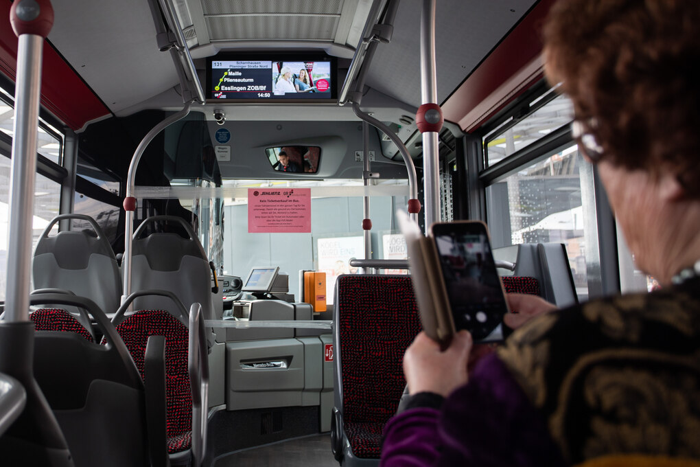 Eine Frau schaut im Bus aufs Handy.