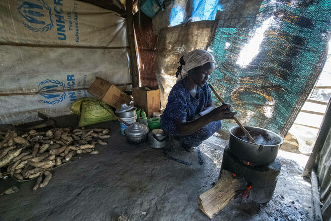 Eine Frau kocht auf ihrem provisorischen Herd in einem Flüchtlingslager