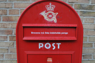 Ein roter Briefkasten der dänischen Post an einer Hauswand