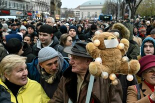Während einer Demonstration hält eine Person aus Protest ein Stofftier mit zugeklebten Mund in die Höhe