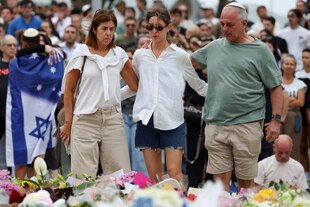 Menschen stehen vor Blumenkränzen