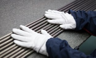 Zwei Hände in weißen Handschuben liegen auf langen Stäben