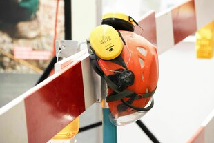 Bauarbeiter Helm und Gehörschutz hängen an einer Bauabschrankung