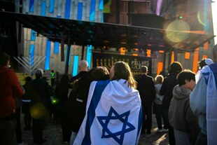 Eine in eine israelische Flagge gehüllte Mutter tröstet ihre Tochter während einer Chanukka-Veranstaltung