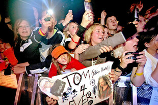 Fans der Band Tokio Hotel stehen dicht gedrängt hinter einer Absperrung und kreischen