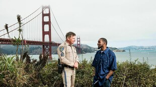 Zwei Männer unterhalten sich, einer trägt eine Polizeiuniform