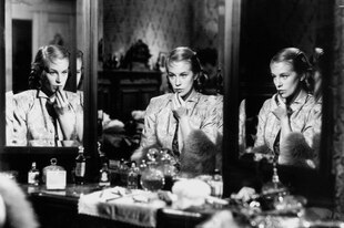 Hildegard Knef sitzt an einem dreiteiligen Schminkspiegel und trägt Lippenstift auf