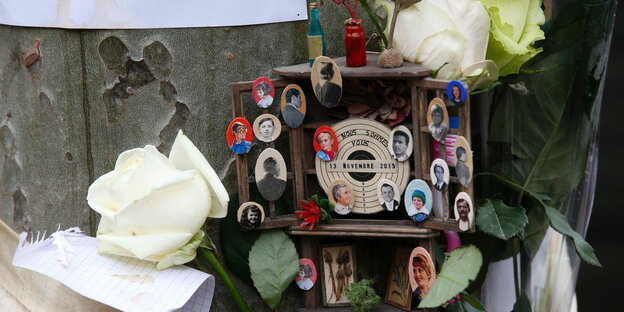 Ein Altar mit kleinen Fotografien von Opfern des Pariser Anschlags, daneben weiße Rosen