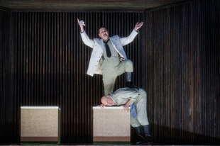 Szene aus „Wozzeck“: Ein Mann tritt auf den Kopf eines anderen, der auf einer Kiste liegt