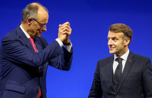 Friedrich Merz in Siegerpose und ein fragend guckender Emmanuel Macron neben ihm