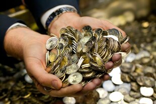 Hände wühlen in einer Kiste mit Zwei-Euromünzen
