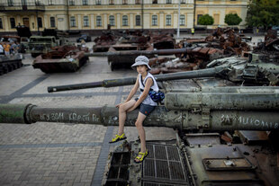 Ein Kind sitzt auf der Kanone eines Panzers