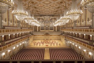 Blick über die leeren Sitzreihen des Konzerthauses zur Bühne, oben Kronleuchter.