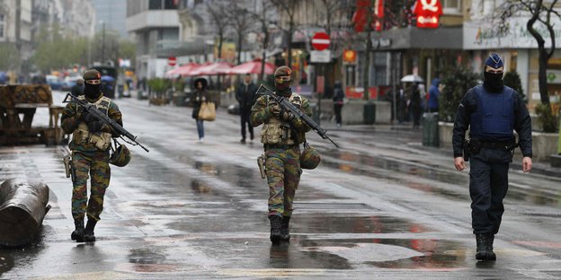 Soldaten patroullieren auf einer regennassen Brüsseler Straße.