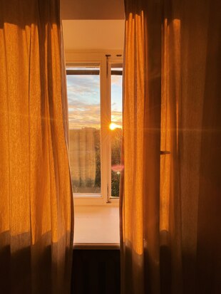 Die Sonne scheint beim Sonnenuntergang durch ein Fenster