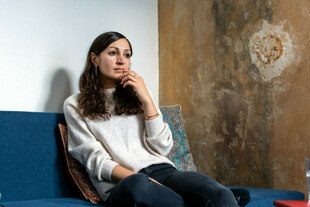 Gilda Sahebi sitzt in einer Wohnung auf dem Sofa