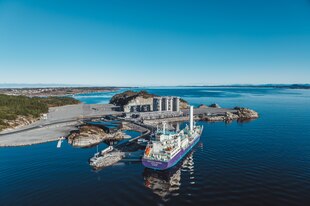 Ein Frachter liegt an der Mole des Energiehafens von Øygarden an der Westküste Norwegens. Der Himmel ist klar, die See rühig