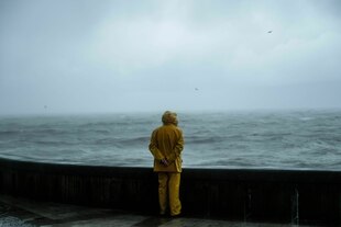 Ein Mann in Ölzeug steht an der Küste der Normandie